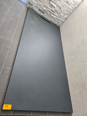 un gros plan d'une cabine de douche avec un sol en carrelage noir