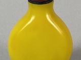 a yellow vase with a red lid sitting on a table