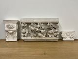 three decorative molds on a wooden shelf next to a white wall
