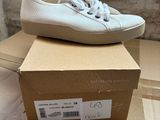 white sneakers with white laces are on top of a cardboard box