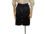 mannequin vêtu d'une chemise blanche et d'une jupe noire, posé sur un support métallique