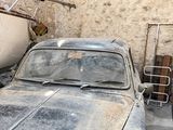 a old car parked in a garage next to a boat