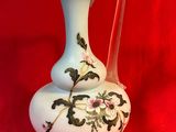 a white vase with a floral design on it on a red background