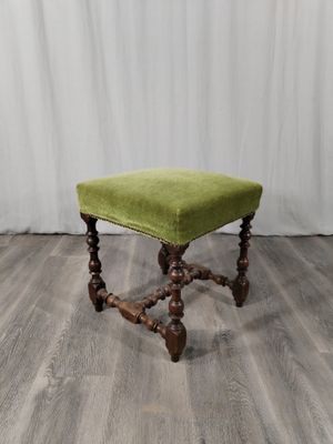 un tabouret rembourré vert posé sur un parquet