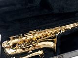 a gold saxophone in a black case on a white background