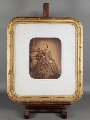 une vieille photo d'une femme en robe, dans un cadre doré