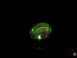 a close up of a green and red fire oplite in a black background