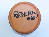 a brown jar with writing on it with a white background