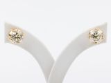 a pair of diamond stud earrings on a stand against a white background