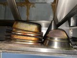 pots and pans are stacked on a metal shelf in a kitchen