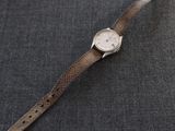 un gros plan d'une montre-bracelet posée sur une surface grise
