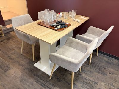 a wooden table with four chairs and a tray with wine glasses on it