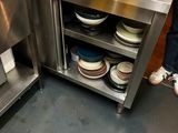 une femme debout derrière un comptoir en acier inoxydable dans une cuisine