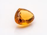 an orange sapphire stone on a white surface