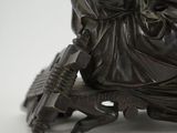 an antique bronze statue of a woman sitting on a chair holding a fan