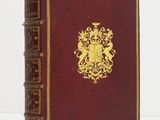 an old book with a gold emblem on it sitting on a white surface