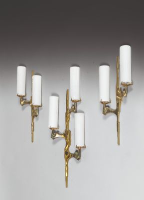 four brass wall sconces with white candles on them against a white wall