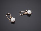a pair of pearl earrings on a black surface