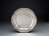 assiette en argent plaqué avec un bord perlé sur un fond gris