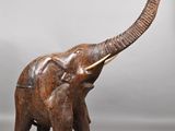 carved wooden elephant with tusks and tusks standing on a gray surface