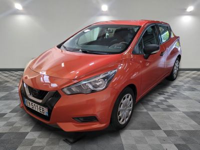 a red nissan versa parked on a checkered floor in a garage
