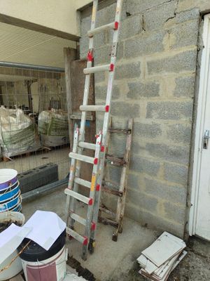 a ladder leaning up against a building next to buckets of paint