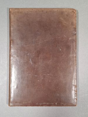 un portefeuille en cuir posé sur une surface blanche, avec un petit trou au milieu