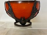 orange glass bowl with black accents on stand against a white background