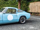 a blue sports car parked in front of a hedge