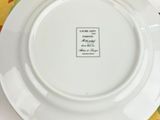 a white plate with a white saucer on a colorful table cloth
