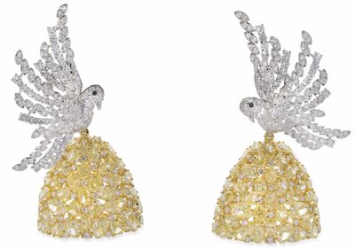 une paire de boucles d'oreilles en diamants jaunes et blancs, ornées d'un oiseau sur le dessus
