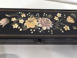 a black box with flowers painted on it sitting on a table