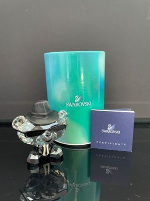 une petite figurine posée à côté d'un coffret de parfum