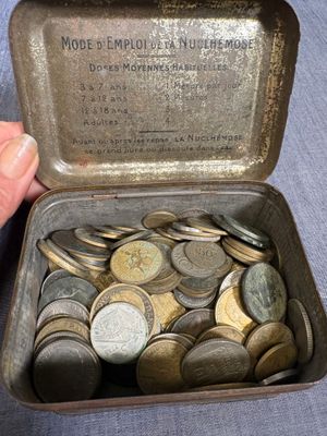 une personne tenant une boîte métallique remplie de pièces de monnaie