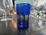 a blue glass sitting on a table next to other wine glasses