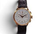 gros plan d'une montre sur une surface blanche avec un bracelet marron