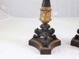 pair of black and gold candlesticks with a clock on each of them