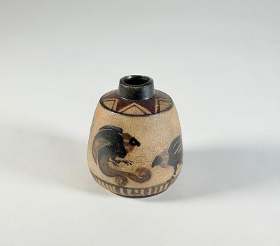 un petit vase avec un motif sur une surface blanche