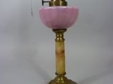 une lampe ancienne en laiton et en verre rose, surmontée d'une ampoule