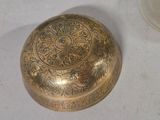 a small brass object sitting on a table next to a cup