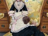 a doll that is sitting on a chair with a teddy bear