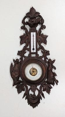 une horloge en bois accrochée au mur à côté d'un thermomètre mural