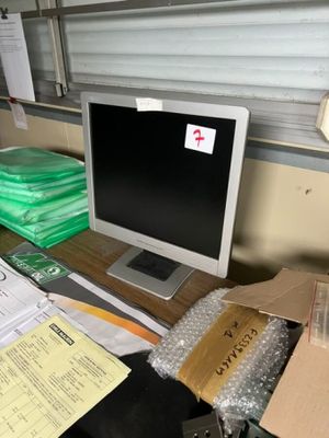 un écran d'ordinateur posé sur un bureau recouvert d'une pile de papiers