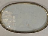 an oval brass tray with a mirror on top of it