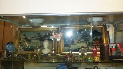 une vitrine en verre avec un tableau accroché au mur derrière