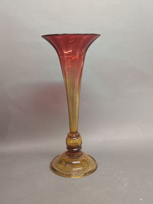 un vase en verre rouge posé sur une table blanche