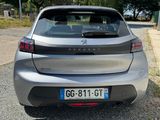the back end of a silver car parked on a gravel road