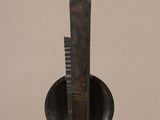 sculpture of a knife and a bowl on a table in front of a beige wall