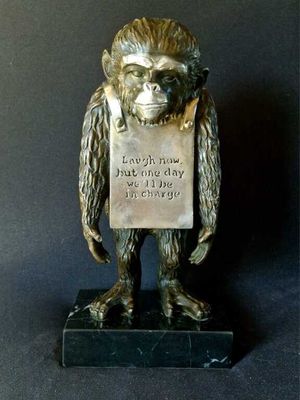 bronze statue of a monkey holding a sign with a quote on it