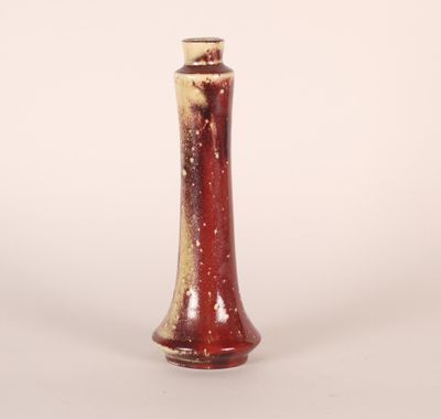 a red and white vase sitting on a white surface